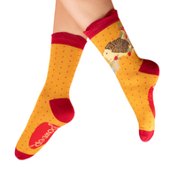 Yellow socks with red accents and a hedgehog worn by a person on a white background