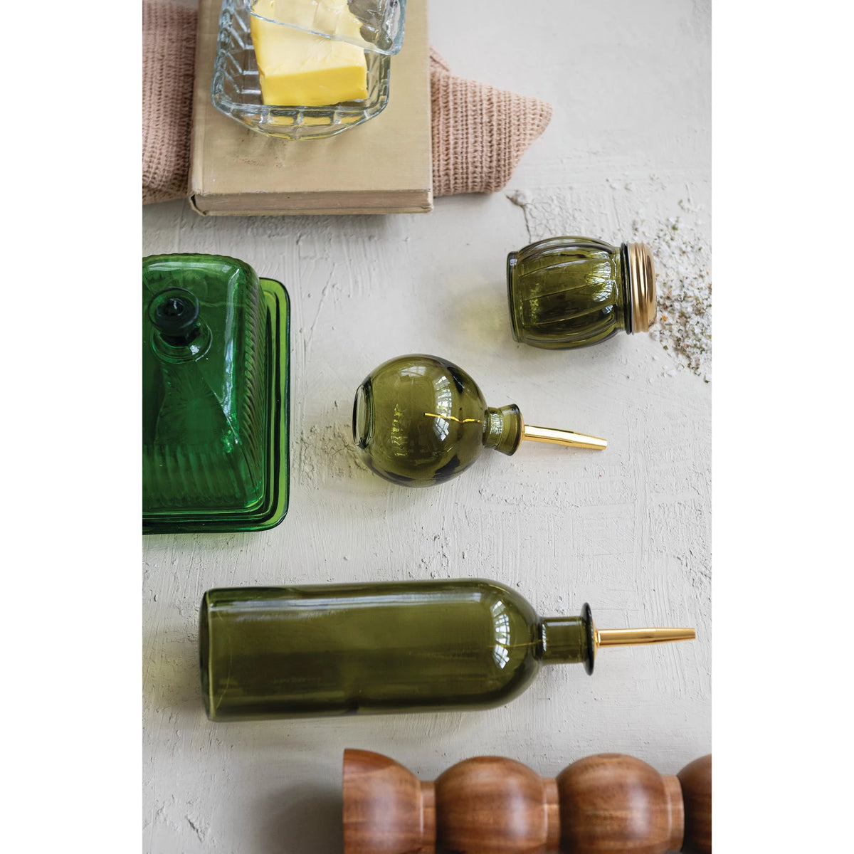 Set of green glass bottles with gold nozzles on a textured surface