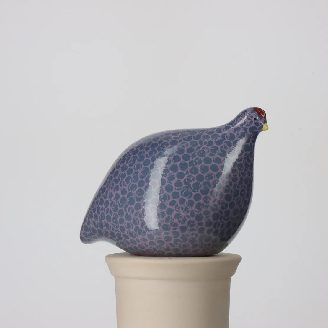 Ceramic quail figurine with a spotted pattern on a white background