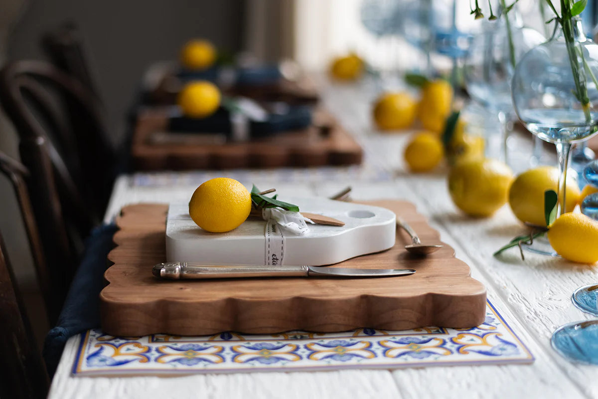 Dining table setting with lemons, a white serving board, and a knife.