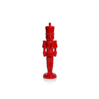 A glossy red nutcracker figurine standing upright on a white background with a soft reflection underneath.