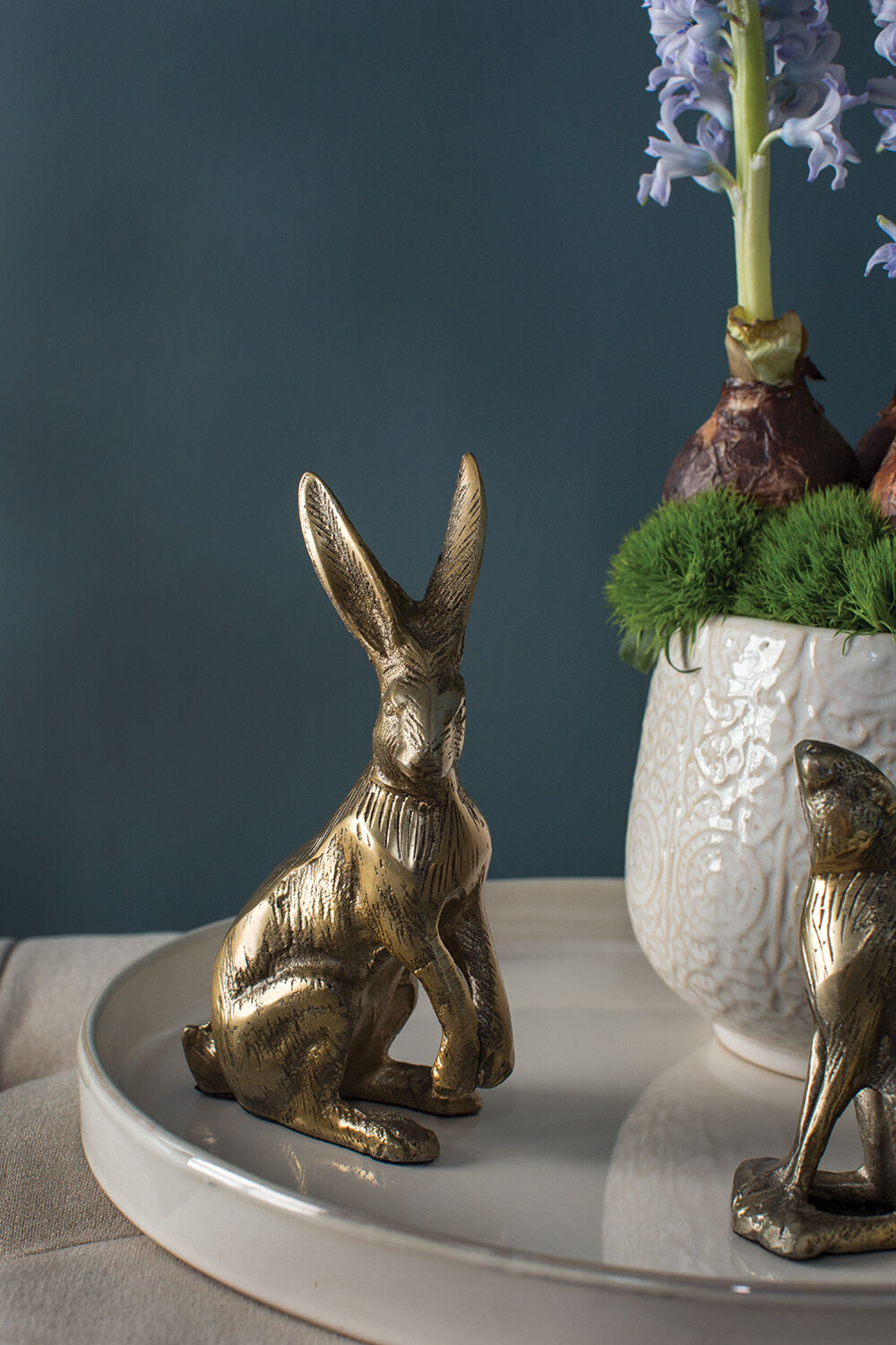 Bronze rabbit figurine on a white surface with a dark background