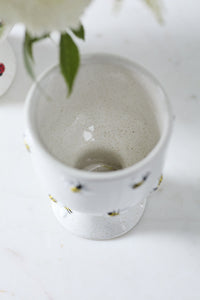 White ceramic compote with bee patterns on a light background