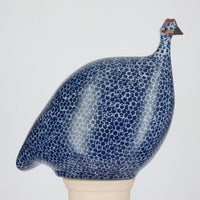 Ceramic guinea fowl figurine with blue and white pattern on a gray background