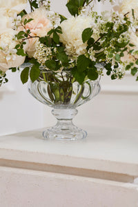 Clear glass vase with white flowers on a light surface