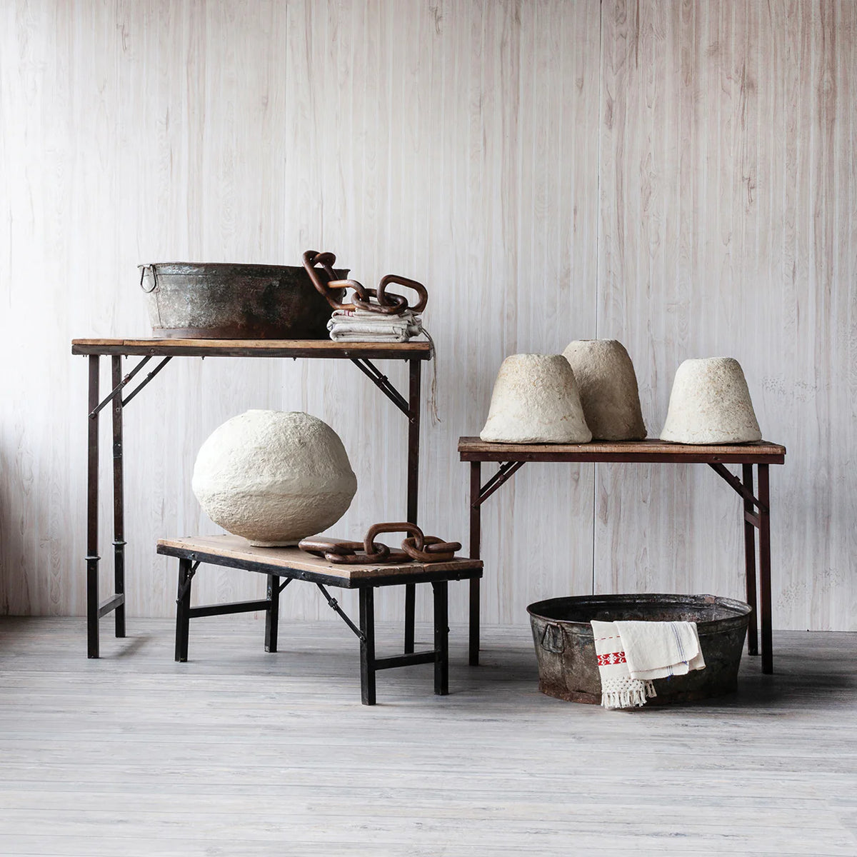 Vintage-style room with wooden tables and rustic decor against a light wooden paneled wall.