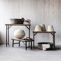 Vintage-style room with wooden tables and rustic decor against a light wooden paneled wall.