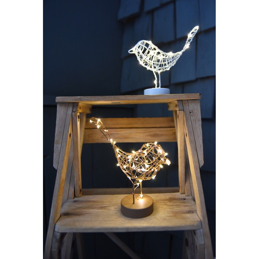 Decorative bird-shaped lights on a wooden stand against a dark background