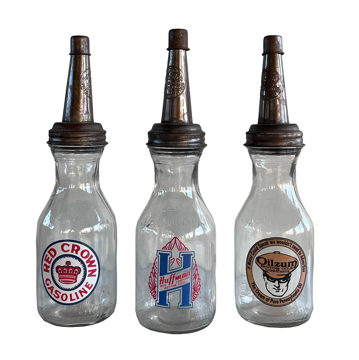 Three vintage-style glass bottles with different labels on a white background