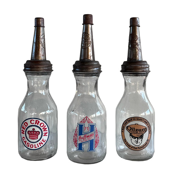 Three vintage-style glass bottles with different labels on a white background