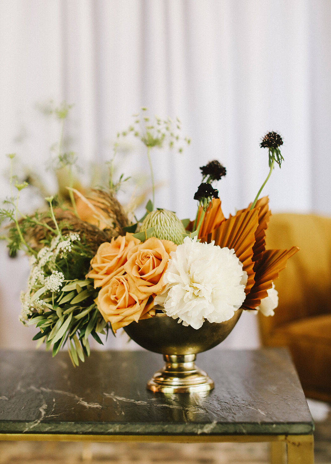 Decorative floral arrangement in a gold vase on a marble surface with a blurred background