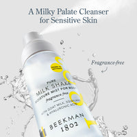 A can of Beekman 1802 Pure Milk Shake Cleanser Moisture Mist for sensitive skin, shown with a spray nozzle releasing mist against a light gray background with water splash graphics and text overlays.