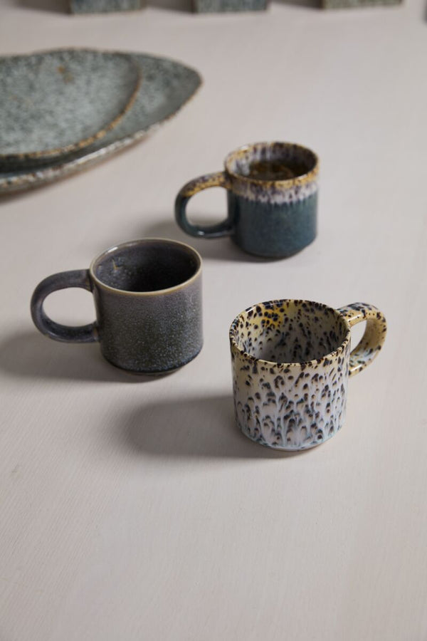 Three ceramic mugs with unique patterns on a light surface