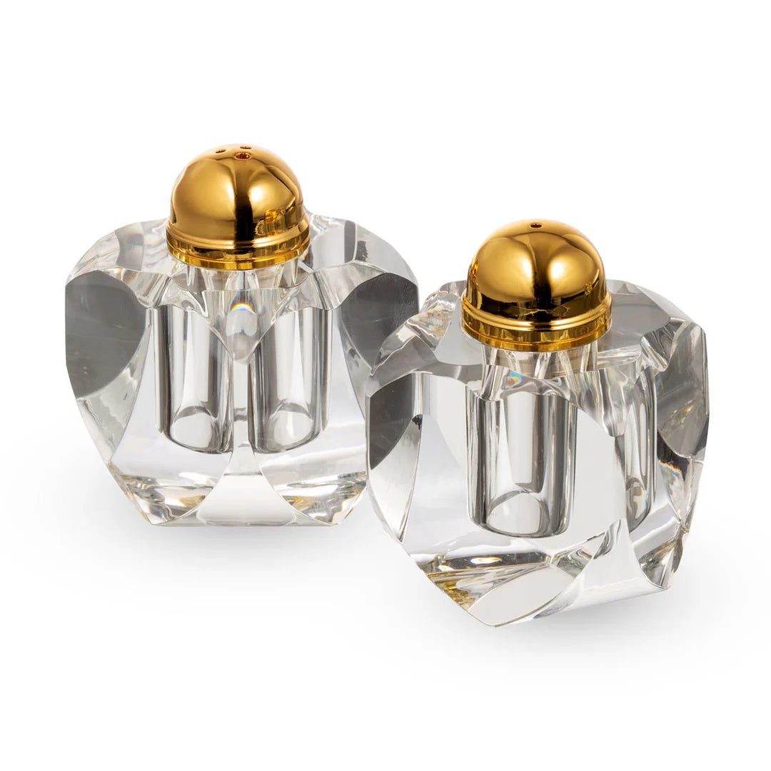 Two crystal salt and pepper shakers with gold lids on a white background