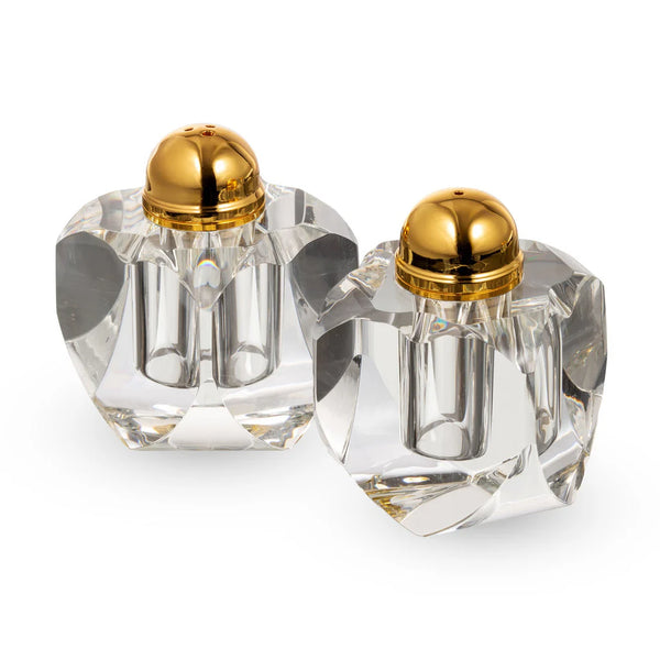 Two crystal salt and pepper shakers with gold lids on a white background