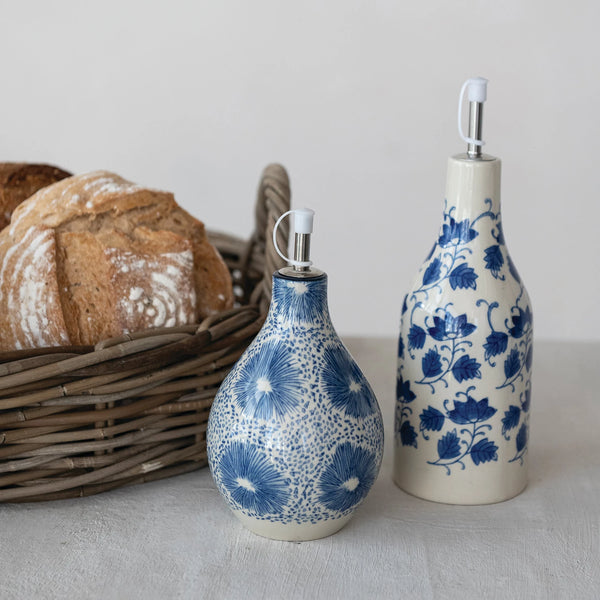 Two ceramic bottles with blue floral patterns next to a basket of bread on a light surface.