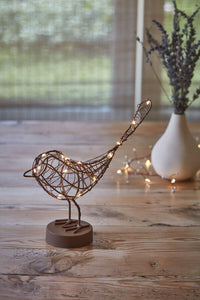 Decorative metal bird with string lights on a wooden surface