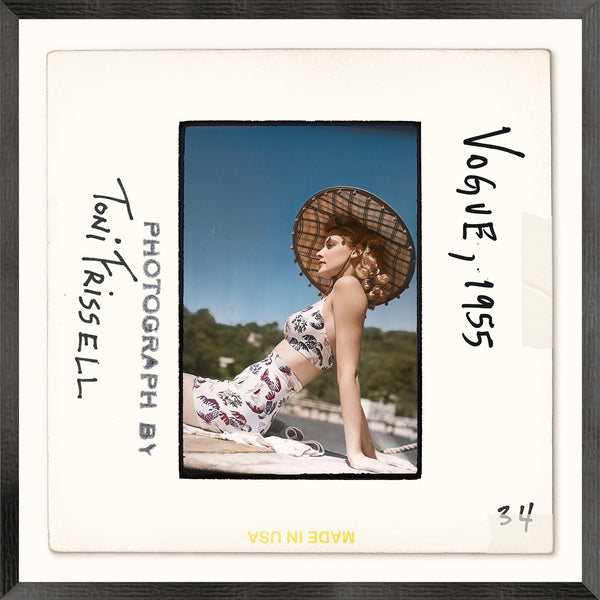 Vintage photograph of a woman wearing a swimsuit and a straw hat with text indicating 'Toni Frissell, Photograph by' and 'Vogue 1955'.