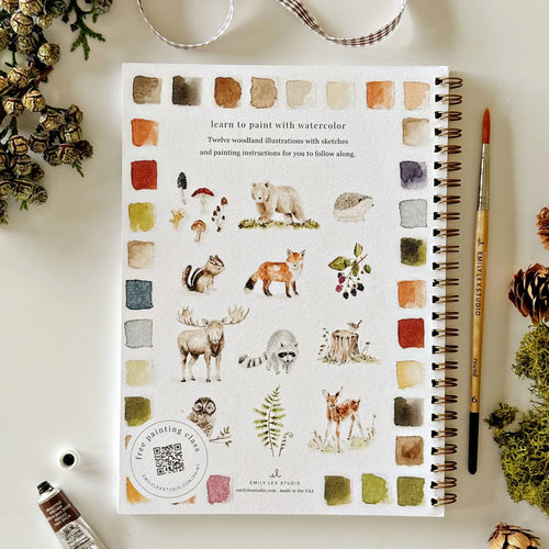 Notebook with nature-themed illustrations on a white surface with art supplies.