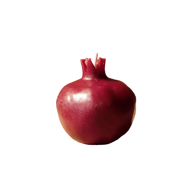 A pomegranate-shaped candle with a deep burgundy red body and crown, with a white background